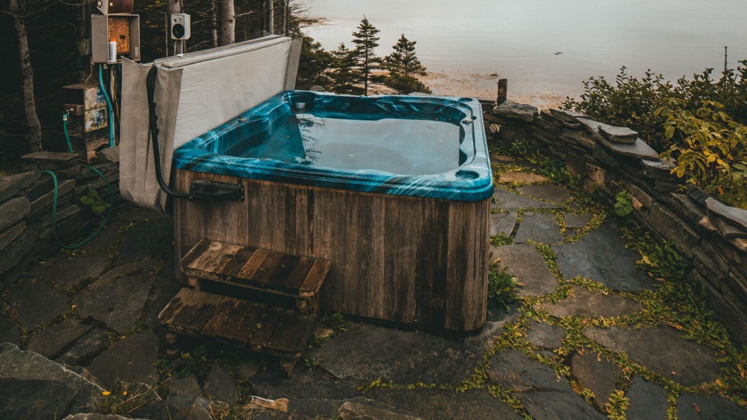 Outdoor hot tub with cover open on stone patio